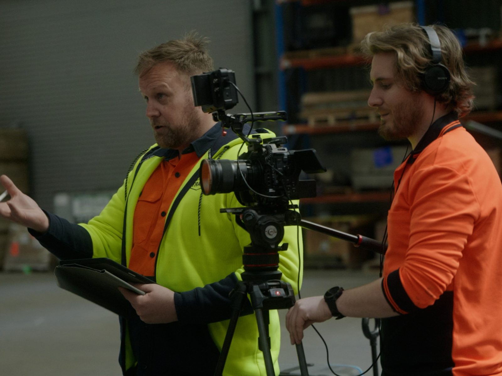 Two of the Lift crew in hi-vis with a cinema camera in a depot