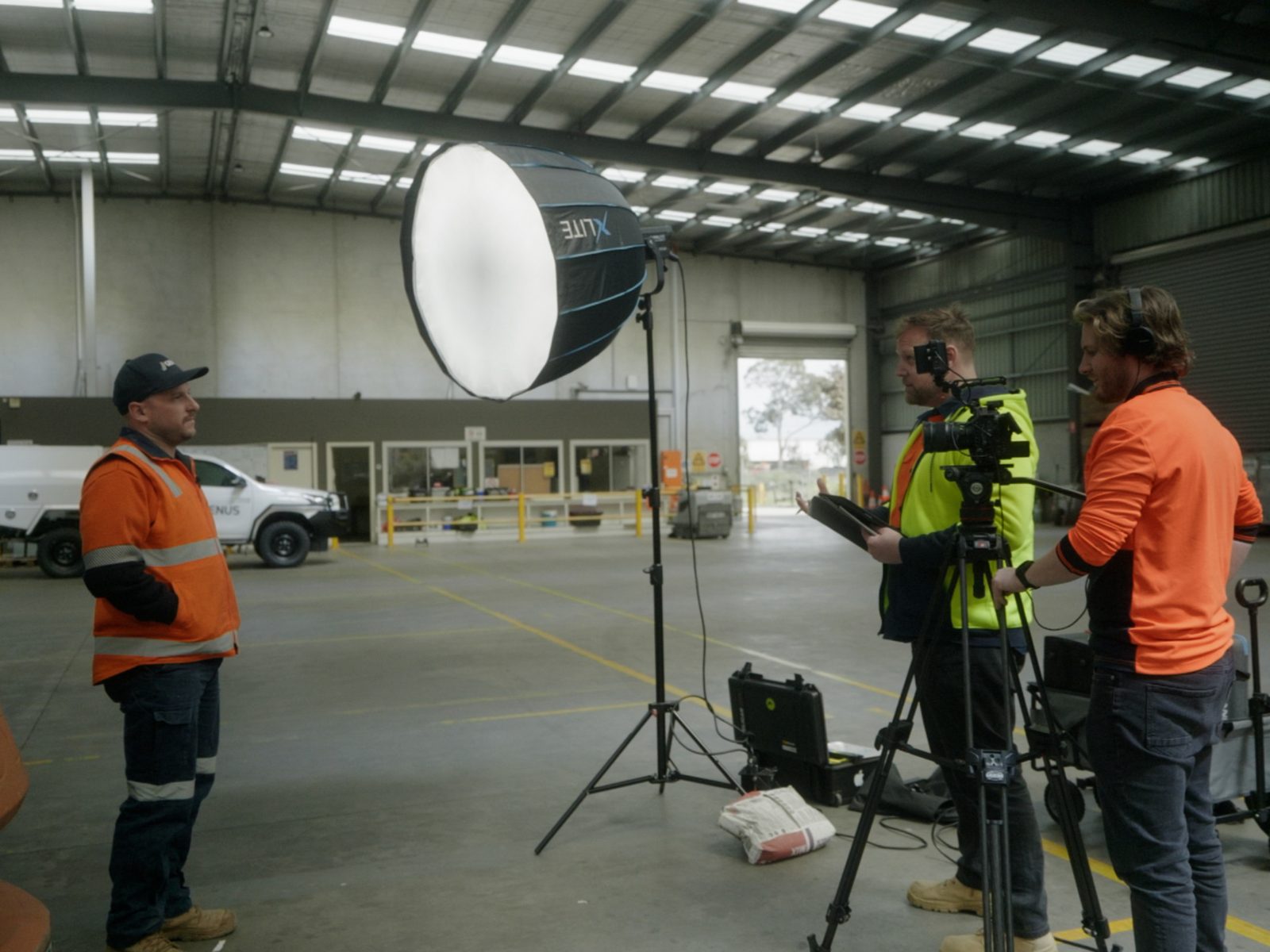 The Lift crew setting up a lit interview with a worker in hi-vis inside a depot