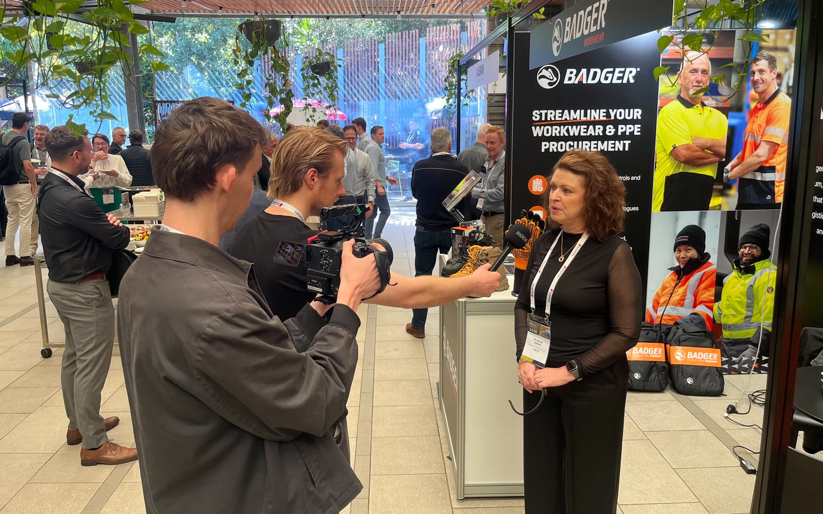 Two of the Lift crew filming an interview with an exhibitor beside her stand at an industry conference