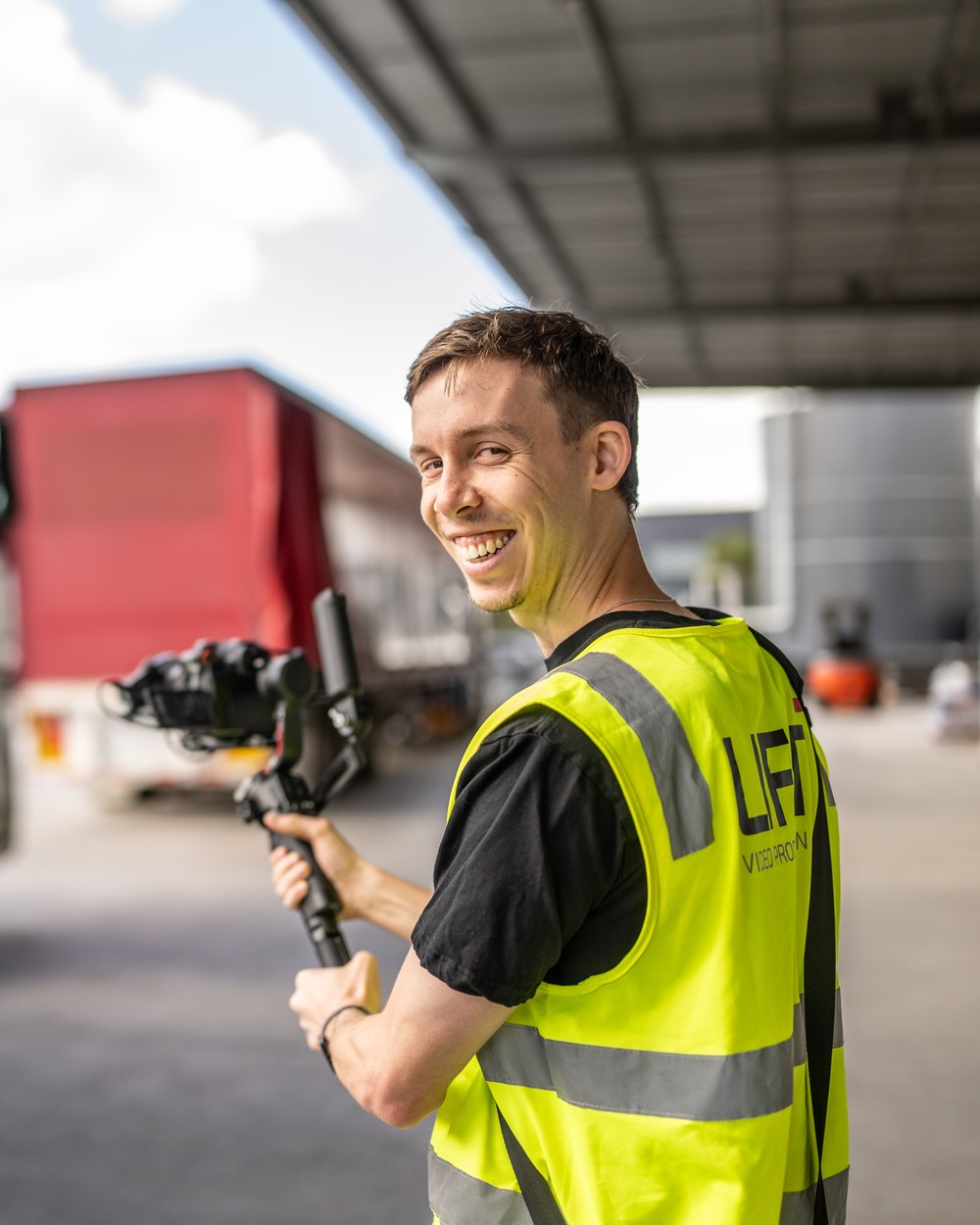 Lift cinematographer on a gimbal in a transport yard with a prime mover behind