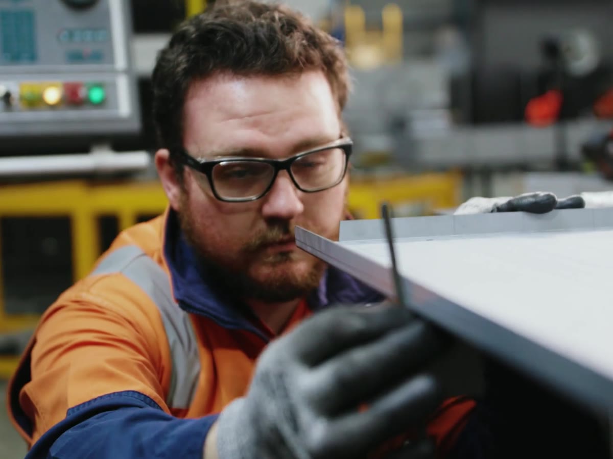 A Mayfield technician in hi-vis checking the edge of a fabricated panel