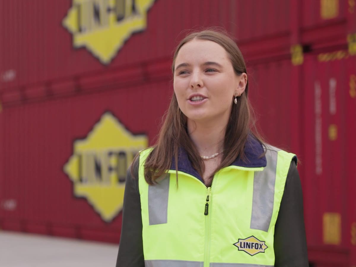 Emma, a Linfox project manager, in hi-vis in front of Linfox containers